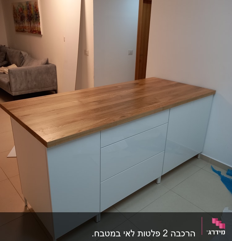 אי מטבח עם משטח עץ ודלתות לבנות